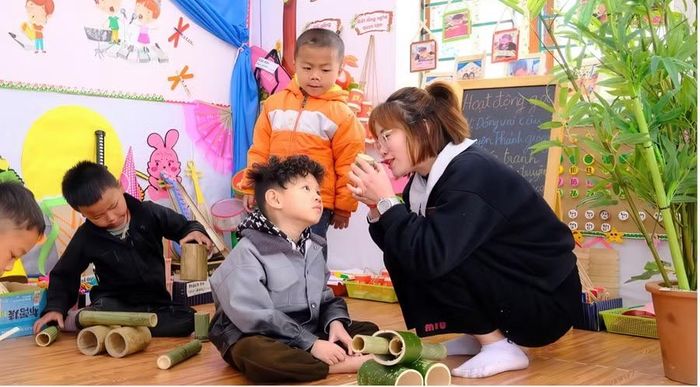 Cô Mai cùng trẻ sử dụng học liệu - Học liệu địa phương trở thành chất liệu để trẻ khám phá và giao tiếp.