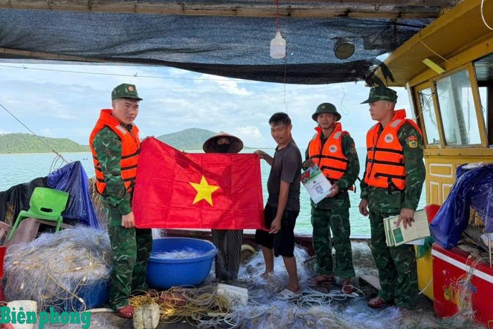 Cán bộ Đồn Biên phòng cửa khẩu cảng Vạn Gia tặng cờ Tổ quốc và tuyên truyền pháp luật cho ngư dân hoạt động trên vùng biển đơn vị quản lý. Ảnh: Đại Dương