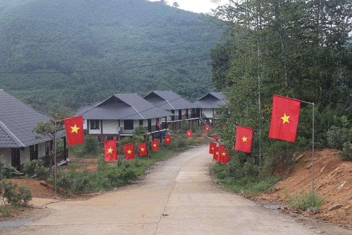 Hai bên đường được cắm cờ hoa đỏ rực, xung quanh khu tái định cư Làng Nủ được dọn dẹp sạch sẽ.