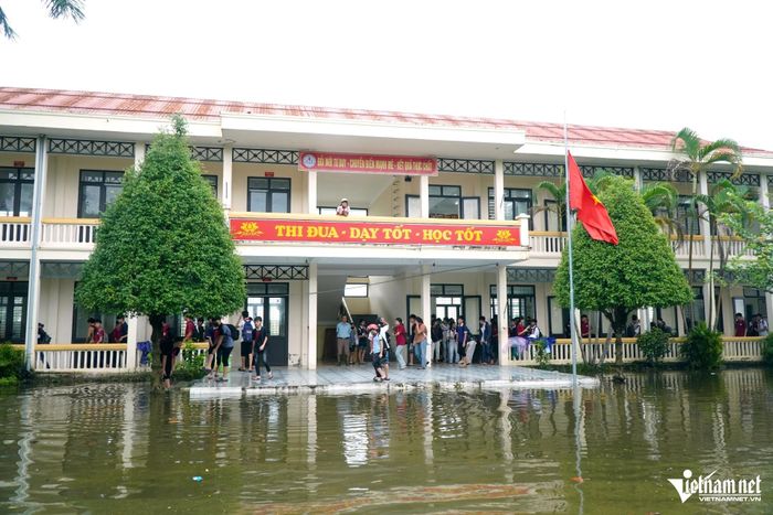 Phải lội qua sân trường ngập nước, học sinh mới vào đến lớp. Ảnh: Lê Dương