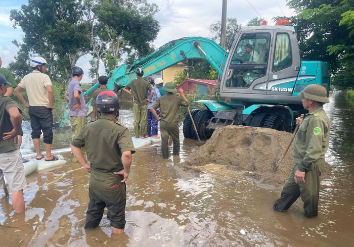 Huy động hàng trăm người và máy móc đắp bờ bao hút nước quanh trường. Ảnh: CTV