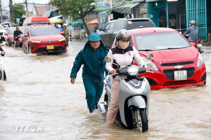 Lực lượng chức năng được bố trí hỗ trợ người dân di chuyển qua đoạn ngập sâu trên quốc lộ 28 qua phường Hàm Thắng. (Ảnh: Nguyễn Thanh/TTXVN) ​