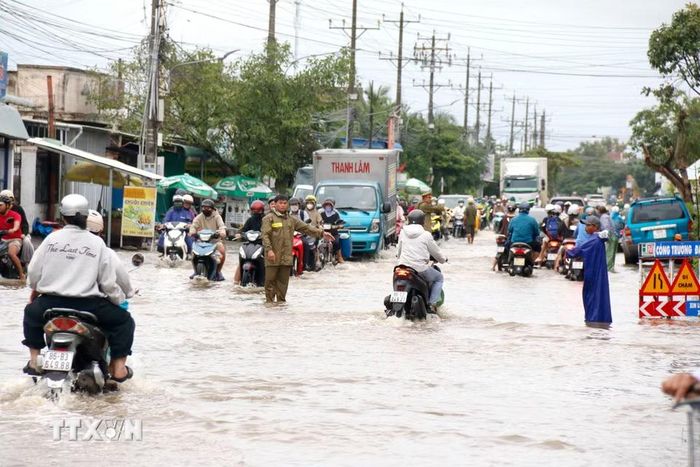 Lực lượng chức năng được bố trí hỗ trợ người dân di chuyển qua đoạn ngập sâu trên quốc lộ 28 qua phường Hàm Thắng. (Ảnh: Nguyễn Thanh/TTXVN)
