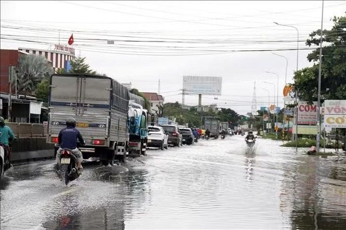 Quốc lộ 1A qua phường Hàm Thắng (Lâm Đồng) nhiều đoạn bị ngập sâu trong nước, các phương tiện lưu thông khó khăn và nhiều xe mô tô bị chết máy. Ảnh: Nguyễn Thanh/TTXVN