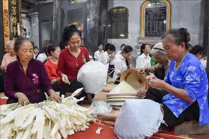 Các nghệ nhân làng Chuông trình diễn nghề làm nón truyền thống. Ảnh: Nguyễn Cúc/TTXVN