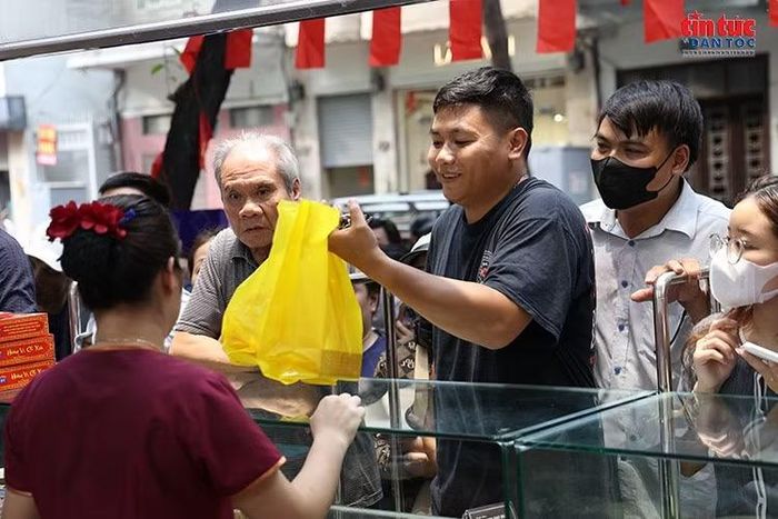 Một khách hàng nhận bánh sau thời gian xếp hàng chờ mua tại cửa hiệu trên phố Thụy Khuê.