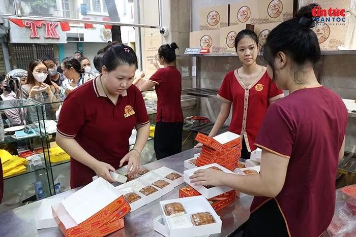 Bên trong cửa hàng, nhân viên liên tục tiếp nhận yêu cầu, đóng gói và giao bánh cho khách.
