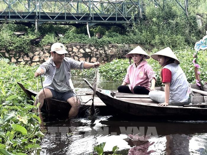 Du khách trải nghiệm cách dỡ lưới chài cá. Ảnh: Hồng Nhung – TTXVN 