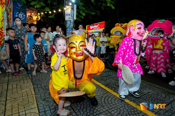 Em nhỏ tươi cười bên ông Địa trong không khí rộn ràng của mùa Trung thu. Ảnh: BẢO LÂM