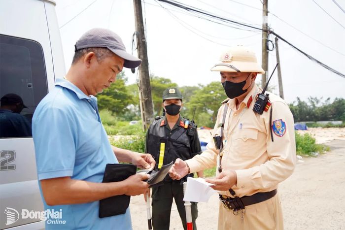 Cán bộ Cục Cảnh sát giao thông kiểm tra giấy phép lái xe và giấy chứng nhận đăng ký xe của người điều khiển phương tiện trên quốc lộ 1A. Ảnh: Lê Duy
