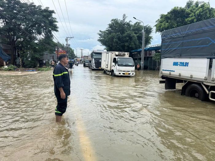 Công an hướng dẫn cho phương tiện di chuyển trên một tuyến đường bị ngập.