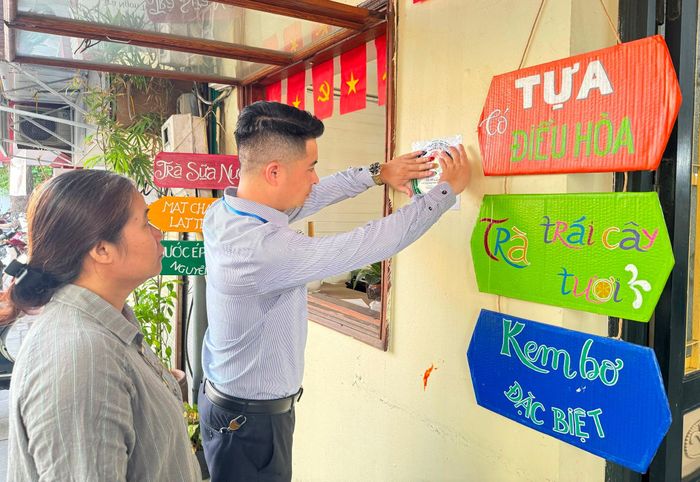 Lực lượng chức năng phường Kim Liên hướng dẫn cơ sở kinh doanh dán niêm yết công khai về cơ đảm bảo ATTP trên tuyến phố Đặng Văn Ngữ. Ảnh: Nguyên Bảo