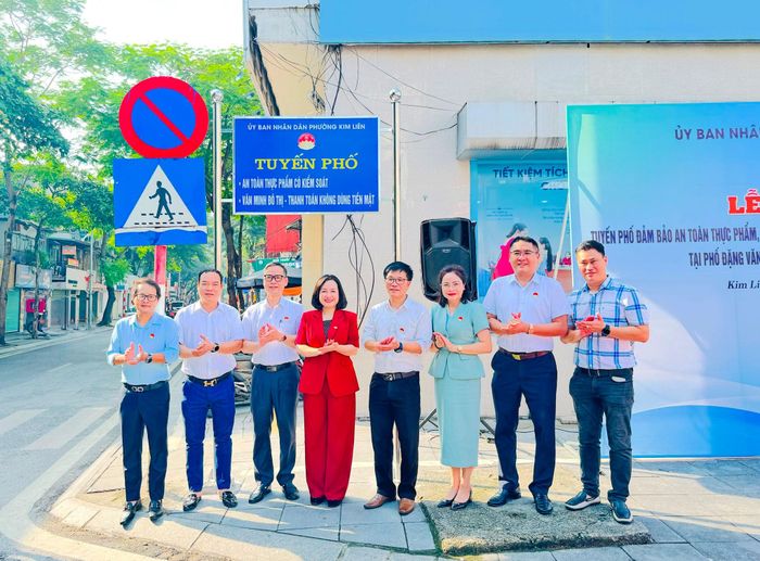 Các đại biểu thực hiện nghi thức gắn biển mô hình “Tuyến phố đảm bảo an toàn thực phẩm, văn minh đô thị - kinh doanh thanh toán không dùng tiền mặt” tại phố Đặng Văn Ngữ. Ảnh: Nguyên Bảo