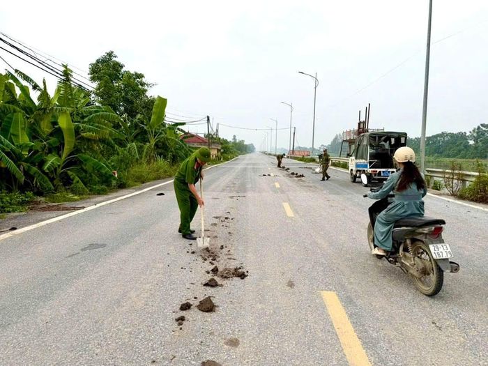 Lực lượng Công an xã Ứng Thiên dọn bùn đất, làm sạch mặt đường. Ảnh: CAX