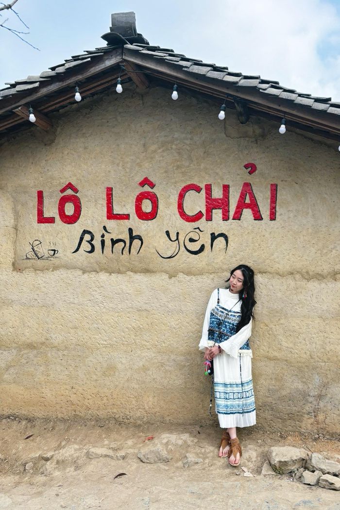 Tôi mặc trang phục của người Lô Lô, đứng trước một căn nhà trình tường tại Lô Lô Chải.