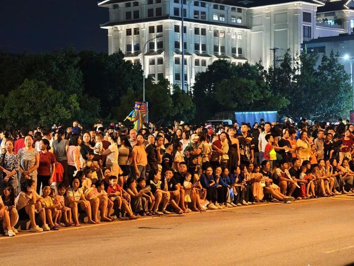 Các em nhỏ, thiếu niên, nhi đồng cùng bố mẹ, ông bà kiên nhẫn ngồi chờ xem diễu hành mô hình đèn lồng khổng lồ