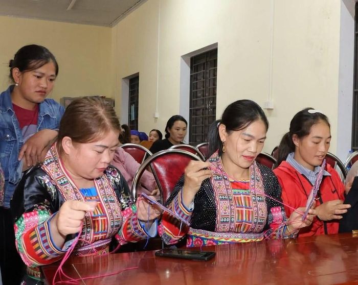 Các thành viên cùng nhau hướng dẫn, thực hành kỹ thuật thêu, tạo hoa văn trên trang phục truyền thống Dao. Ảnh: Minh Huệ