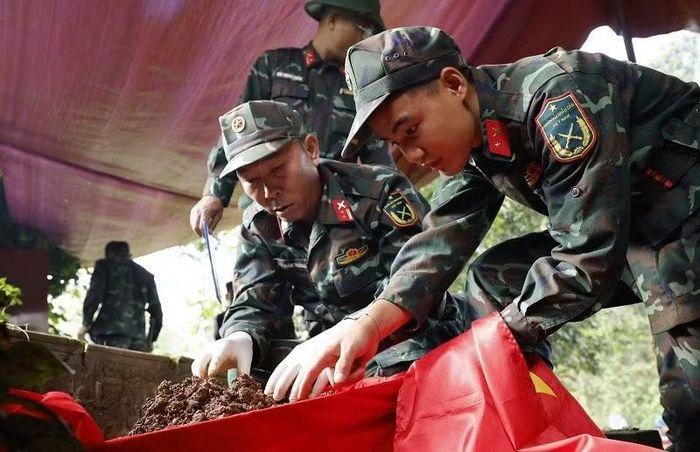 Trung tá Đào Xuân Trường (bên trái ảnh) đang cẩn thận cất bốc hài cốt liệt sĩ. (Ảnh: LÊ LAN)