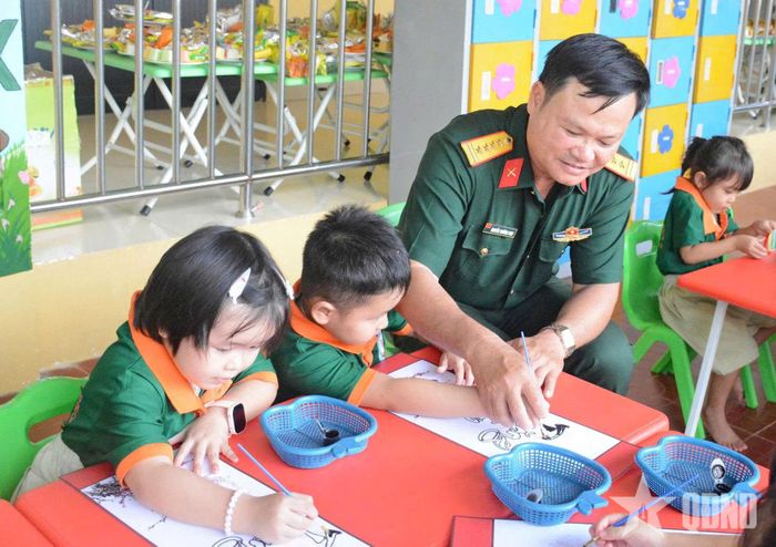Đại tá Nguyễn Trường Vinh, Đoàn trưởng Đoàn Kinh tế - Quốc phòng 78 hướng dẫn các cháu Trường Mầm non 25-3 viết thư pháp.