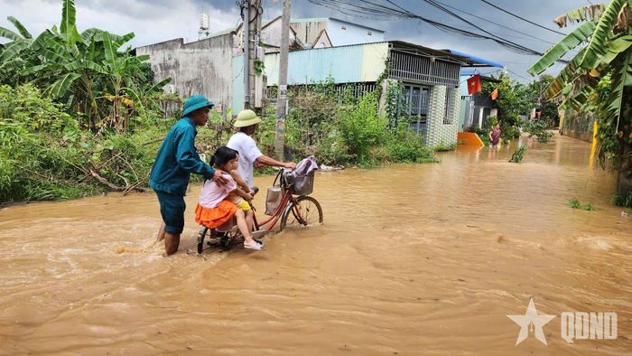 Hỗ trợ người dân đưa các cháu nhỏ đến nơi tránh trú. 