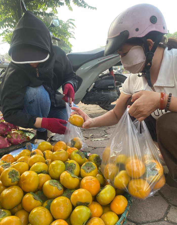 Người dân chọn mua hồng giòn để bày mâm ngũ quả Tết Trung thu, sáng 25-9 tại chợ Dương Nội (TP Hà Nội). Ảnh: PHÚC HẬU