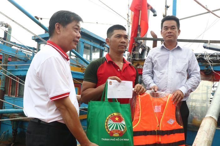 Ông Đỗ Ngọc Huy (bên trái), Phó Chủ tịch Thường trực Hội Nông dân TPHCM, trao quà và cờ Tổ quốc cho ngư dân có hoàn cảnh khó khăn tại xã Bình Châu