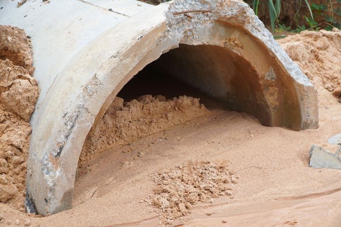  Miệng cống thoát nước qua đường dân sinh bị đất, cát chặn gây ngập. Ảnh: PHÚ NGÂN 