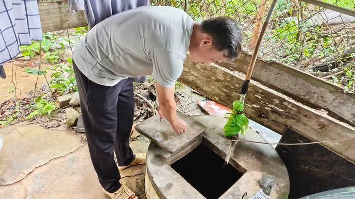 Thầy Nguyễn Thành Tâm bên giếng nước bị đục sau mưa tại khu nhà tập thể giáo viên. (Ảnh: T.H)