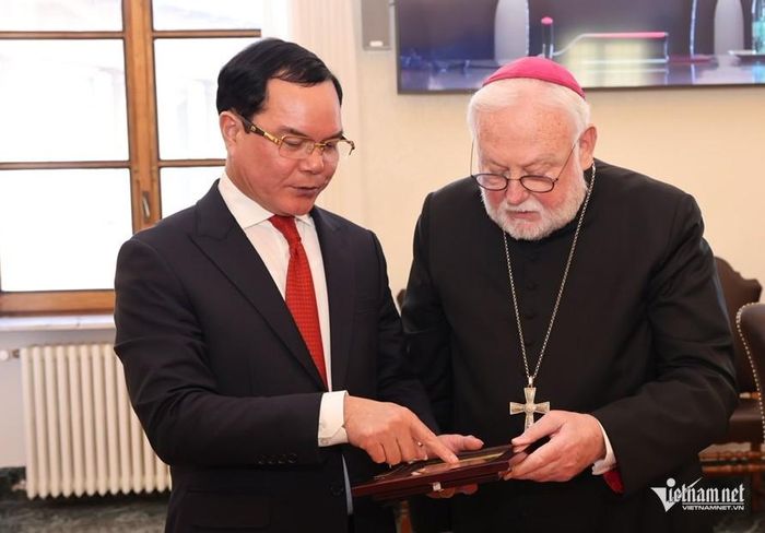 Bộ trưởng Nguyễn Đình Khang giới thiệu với Bộ trưởng Bộ Ngoại giao Tòa thánh Vatican - Tổng Giám mục Paul Richard Gallagher ý nghĩa quà tặng lưu niệm được Đoàn công tác Bộ Dân tộc và Tôn giáo Việt Nam tặng Đức Giáo hoàng.