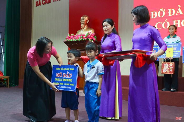 Lãnh đạo UBND xã Cẩm Trung và đại diện các đơn vị nhận đỡ đầu trao biểu trưng hỗ trợ cho các cháu trẻ mồ côi.