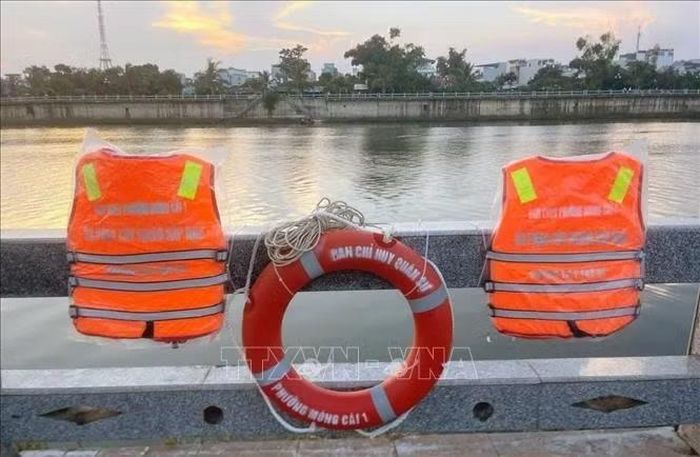 Ban Chỉ huy Quân sự phường Móng Cái 1 tiến hành treo áo phao, phao cứu sinh trên cầu vượt sông. Ảnh: TTXVN phát