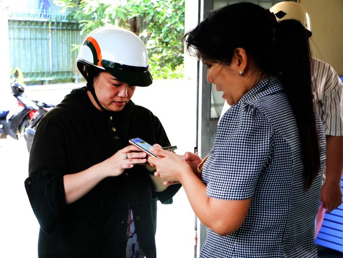 Bà Vũ Thị Thúy Hằng, Trưởng Khu vực 5 (phường Vị Tân, thành phố Cần Thơ) hướng dẫn người dân sử dụng điện thoại thông minh thực hiện dịch vụ công trực tuyến. Ảnh: Duy Khương/TTXVN