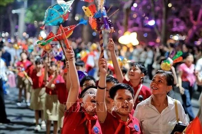 Các em nhỏ Trường Tiểu học Nguyễn Du hào hứng giơ cao những món đồ chơi Trung thu trong đoàn rước quanh hồ Hoàn Kiếm. Ảnh: Phạm Tuấn Anh/TTXVN