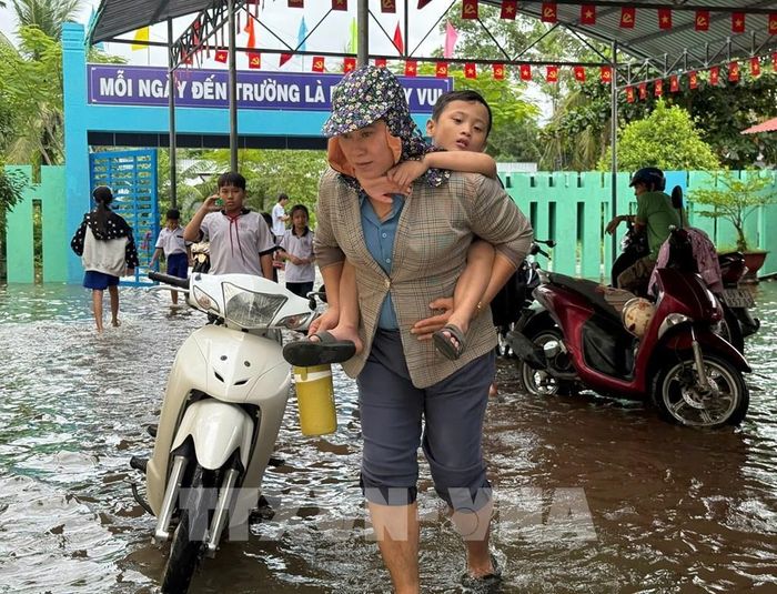 Phụ huynh đón học sinh về khi trường bị ngập. Ảnh: Tuấn Phi - TTXVN