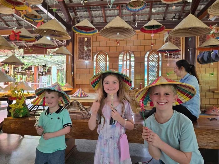Các em nhỏ thích thú khi đội nón lá và được tặng đồ chơi nặn từ đất sét khi tham quan Làng nghề Trường Sơn (Nha Trang)