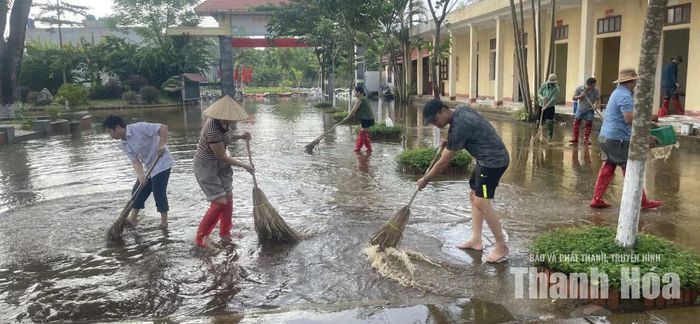 Giáo viên Trường THCS Đồng Tiến khẩn trương quét dọn sân trường sau khi nước rút.