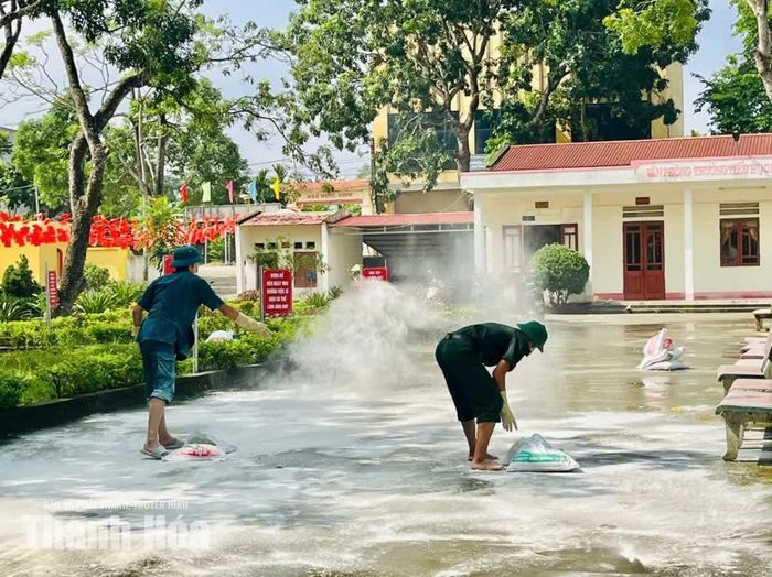Sau khi vệ sinh khu vực sân, lực lượng quân sự, dân quân tự vệ hỗ trợ Trường Tiểu học Đồng Tiến rải vôi bột tiêu độc khử trùng.