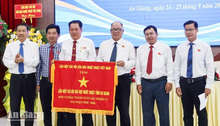Phó Chủ tịch Thường trực Liên hiệp các Hội Văn học Nghệ thuật Việt Nam Đoàn Thanh Nô (bìa trái) trao Cờ thi đua cho Liên hiệp các Hội Văn học Nghệ thuật Việt Nam tỉnh An Giang.