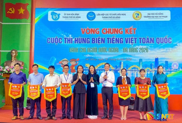 Ban tổ chức trao cờ lưu niệm cho 7 đội tham dự Vòng chung kết Cuộc thi hùng biện tiếng Việt toàn quốc dành cho người nước ngoài - Đà Nẵng 2026. Ảnh: KHÁNH LINH