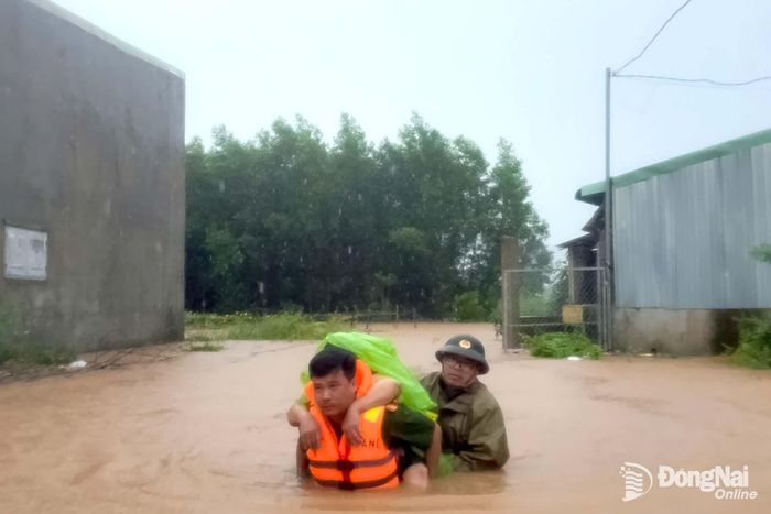 Cán bộ, chiến sĩ Công an xã Bình Minh hỗ trợ đưa người dân tại khu vực ngập đến nơi an toàn. Ảnh: CAX