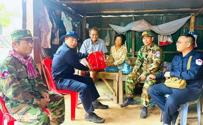 Thượng tá Vũ Văn Thọ (thứ 2 từ trái qua) thăm, tặng quà các nhân chứng cung cấp thông tin về mộ liệt sĩ. Ảnh: ĐVCC