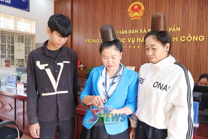 Công chức Trung tâm Phục vụ hành chính công xã Phiêng Pằn hướng dẫn người dân sử dụng dịch vụ công trực tuyến qua điện thoại thông minh.