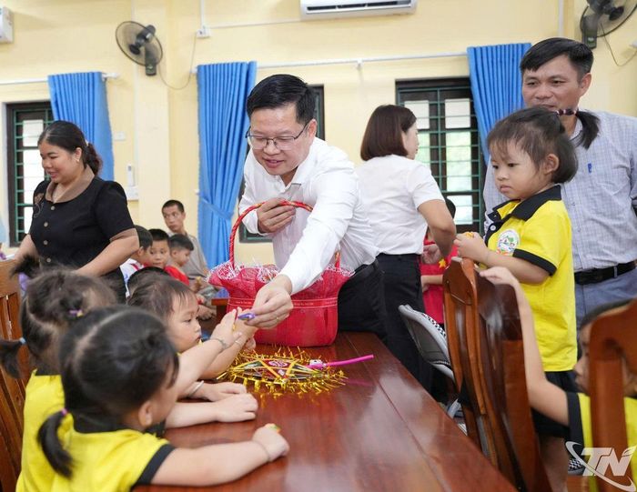 Đồng chí Đinh Quang Tuyên chia bánh kẹo cho thiếu nhi.