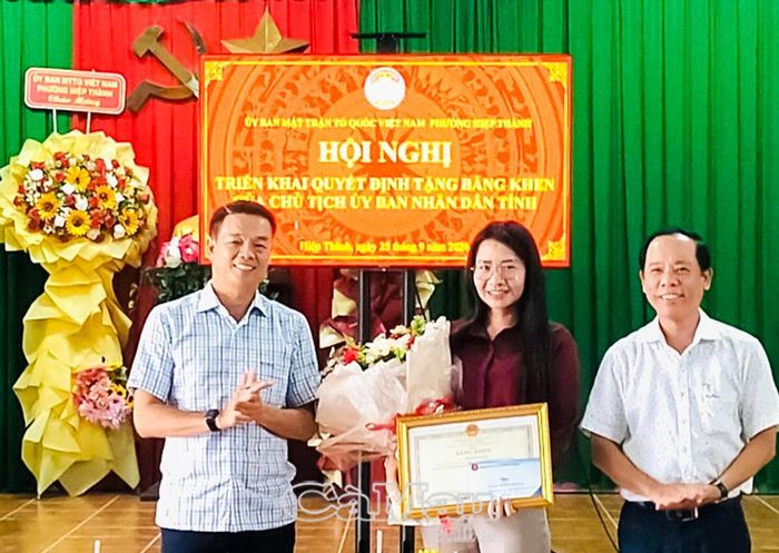Đồng chí Nguyễn Nam Phong, Phó Trưởng ban Tuyên giáo Tỉnh uỷ (bên trái) và đồng chí Phan Thanh Vũ, Phó Bí thư Thường trực Đảng uỷ phường Hiệp Thành, trao Bằng khen và hoa chúc mừng đồng chí Thạch Thị Hoa.