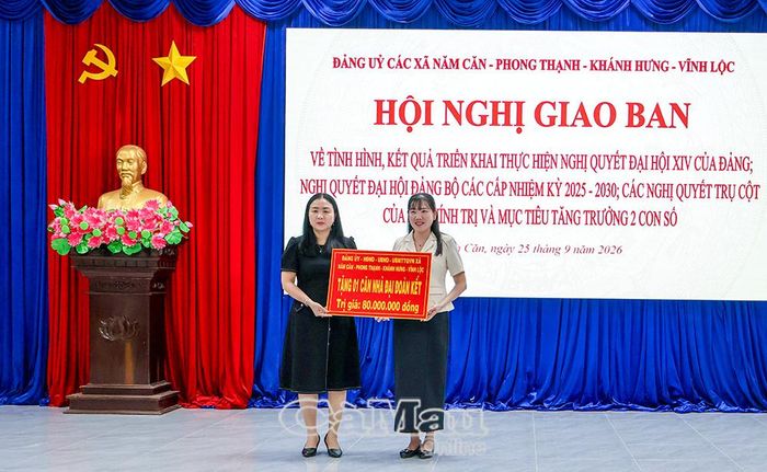 Đồng chí Nguyễn Cẩm Tú, Bí thư Đảng uỷ xã Phong Thạnh (trái), đại diện các xã trong cụm, trao bảng tượng trưng tặng căn nhà Đại đoàn kết cho xã Năm Căn.