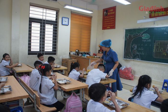 Giáo viên chủ nhiệm hỗ trợ kê lại bàn ghế trong phòng học, tạo thành không gian ăn trưa vừa vặn, sạch sẽ cho các em học sinh lớp 1.