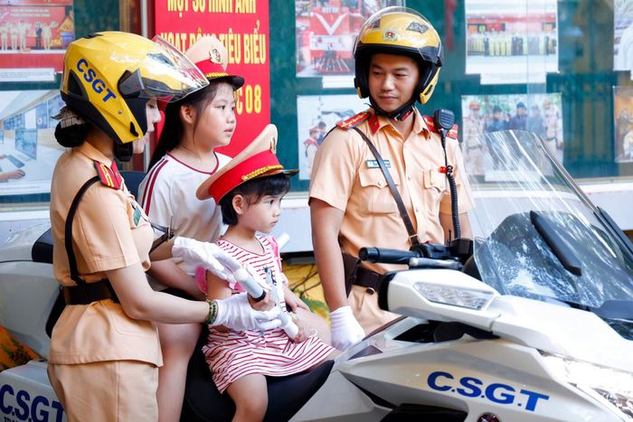 Chiến sĩ CSGT ân cần hỗ trợ, hướng dẫn các cháu nhỏ trải nghiệm an toàn trên xe đặc chủng