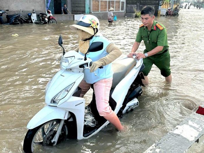 Lực lượng công an TP. Cần Thơ hỗ trợ người dân đi lại những nơi bị ngập do triều cường