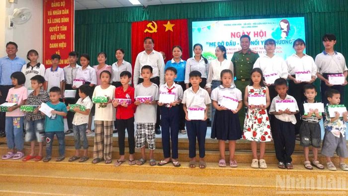 Thiếu tá Nguyễn Thành Sang phối hợp chính quyền địa phương tặng quà các “Con nuôi Công an xã”. (Ảnh: ĐẶNG THANH)