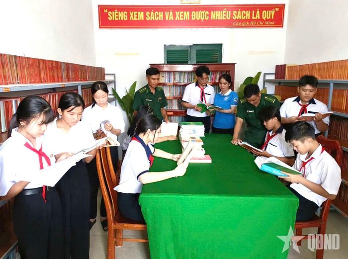 Cán bộ Đồn Biên phòng Đất Mũi cùng các em học sinh tìm hiểu sách, báo tại phòng đọc của đơn vị.